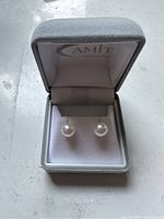 Pearl stud earrings presented in an Amit branded grey jewelry box with white interior.