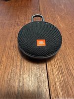 Front top view showing the black mesh fabric speaker grill and orange JBL logo.