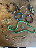 Overview of all jewelry items on a wooden surface including bracelets, necklace, brooch, and hair clip.