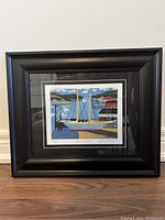 Front view of framed art print showing colorful harbor scene, double mat, and black frame