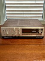 Front view showing silver metal panel with controls, buttons, and display, with wood grain top.