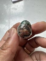 Close-up of the silver ring front showing the irregular dark stone with rough texture.