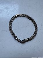 Sterling silver twisted rope design link bracelet laid flat in a round shape showing the full bracelet and clasp detail.