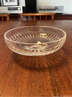 Clear crystal bowl with detailed cut glass design sitting on wooden surface