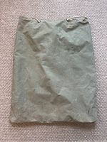 Front view of vintage green canvas duffle bag showing overall shape and drawstring closure top.