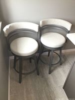 Two gray metal swivel bar stools side by side
