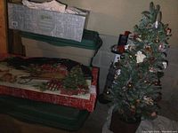Photo showing three large storage totes stacked, Christmas themed mats on top, in a basement setting.