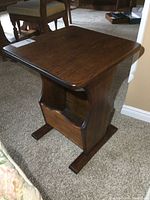 Solid wood end table with dark finish shown at an angle, highlighting top surface and magazine storage area at the bottom.
