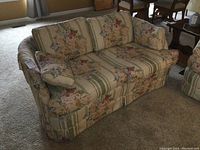Front angle showing loveseat's floral fabric upholstery with removable cushions.