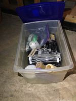 Clear plastic tote filled with various painting supplies including rollers, trays, brushes.