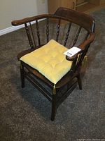 Front view of vintage pub style wooden chair with yellow tufted cushion.