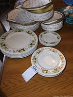 Overall view of the plates stacked with fabric keepers behind them on a wooden table, showing the floral pattern and the keeper covers.