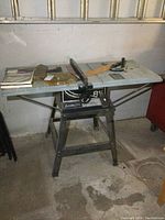 Full view of Delta 8 1/4 professional table saw on metal stand with accessories and books on top