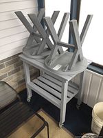 Rectangular painted wood table on casters with two round side tables placed upside down on top.