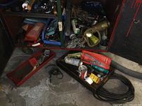 View of several open tool cabinet drawers showing chains, rope, hand tools, and various small items inside
