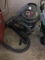 Front view showing Craftsman brand and 4.0 HP label on wet/dry vacuum with attached hose.