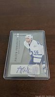 Two images showing the front of two Andy Wozniewski rookie hockey cards with autograph encased in plastic holders. Cards feature the player in Toronto Maple Leafs uniform, white jersey #56, labeled Prized Prospects from Upper Deck.