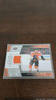 Front of the hockey trading card featuring Brayden Schenn in Philadelphia Flyers uniform with orange game-used jersey swatch embedded.