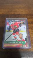 Front view of Connor Bedard Chicago Blackhawks hockey card, showing player in red jersey and team logo.