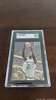 Front view of Kevin Garnett 1995-96 Fleer Metal rookie card graded 7 by SGC in plastic case.