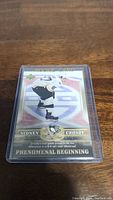 Front view of Sidney Crosby rookie hockey card featuring action image, team logo, and 'Phenomenal Beginning' text.