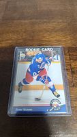 Front side of Teemu Selanne YoungGuns rookie hockey card in protective sleeve on wooden surface.