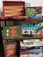 Photo showing multiple board games including backgammon set, poker dice, Yahtzee Texas Hold'em, M*A*S*H, Toronto in a Box, Mouse Trap, Operation, Risk, and a magnetic chess set.