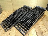Pair of black plastic car ramps with grid support, viewed from top down.