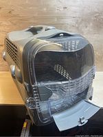 Front view showing transparent door open downward revealing interior, ventilation slots visible on sides.