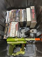 Overview of computer game titles, PlayStation games, and two game controllers in a box.