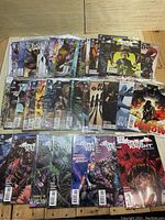 Large collection of DC and Marvel comics in clear plastic sleeves, laid out on a wooden surface