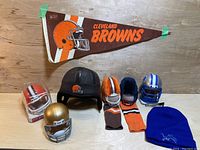 Wide shot of all items in lot showing football memorabilia including pennant, helmets, ear muffs, and knit hat.