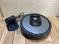 Top view of iRobot Roomba robot vacuum and charging station on wooden floor.