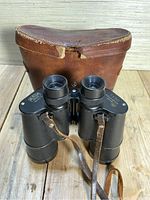 Front view of Carl Wetzlar Marine binoculars with leather strap on wooden surface