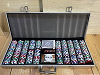 Open poker set case displaying poker chips, decks of cards, dice, and dealer button.