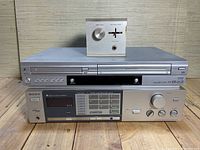 Full front view of both Sony units stacked with a small audio controller on top, showing model features and condition