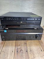 Front view of Sony 5-disc CD player stacked on top of Sony Digital Audio/Video Control Center, showing buttons, display screens, and overall condition.