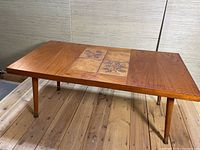 Front and top view of a rectangular teak wood coffee table showcasing the natural grain and central tile inlay with botanical patterns.