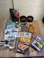 Wide shot showing all vintage automotive tools, magazines, manuals, and plaques arranged on wooden floor.