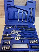 Close-up view of Westward socket set components organized in blue molded case highlighting sockets, ratchet handles, combination wrenches, pliers, Allen wrenches, and screwdriver accessories.