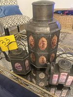 Front view of the large tea caddy flanked by two teapots, showing metal framework and painted glass panels