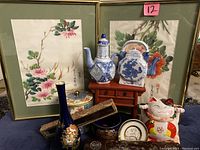 Photo of the lot items including framed silk paintings, porcelain pieces, lucky cat bank, vase, and chopsticks case.