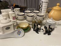 Photo showing assorted vintage tableware including coffee cups, ceramic containers, and decorative salt and pepper shakers.