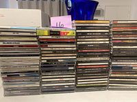 Stacks of assorted music CDs including various genres and popular artists.