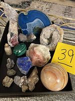 Photo showing a collection of geodes, polished stones and mineral specimens arranged on a black surface.