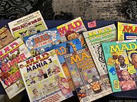 Eleven MAD Magazine special editions and collector series issues laid out, showing various themed covers such as Super Heroes, Mania 3, and collector's items with pull downs.