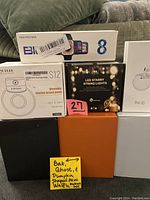 Photo showing a white box for wearable electric breast pump S12, a black box for LED starry string lights with remote, a large orange box containing Halloween themed mini waffle makers, and a white box for wireless in-ear headphones.
