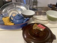 Photo showing assortment of vintage bake and serving ware including ceramic, glass, and metal pieces, decorative yellow ceramic boot, and a blue ceramic oval baking dish with lid.