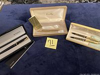 Full lot showing all pens in their respective boxes and cases on blue fabric background