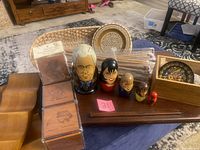 Photo showing 2 wooden wine bottle holders, set of mahogany coasters, new knitting needles in packaging, wooden lap desk/storage box, souvenir plates in box, and Russian nesting dolls